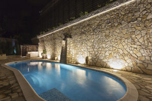 Private swimming pool at night with outdoor lighting.