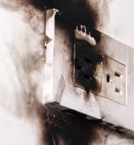 Burned, blackened outlet on a white wall.