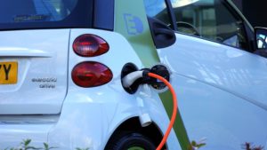 Electric car charging station charging a small white electric vehicle.